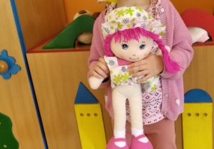 Dziewczynka stoi z lalką.